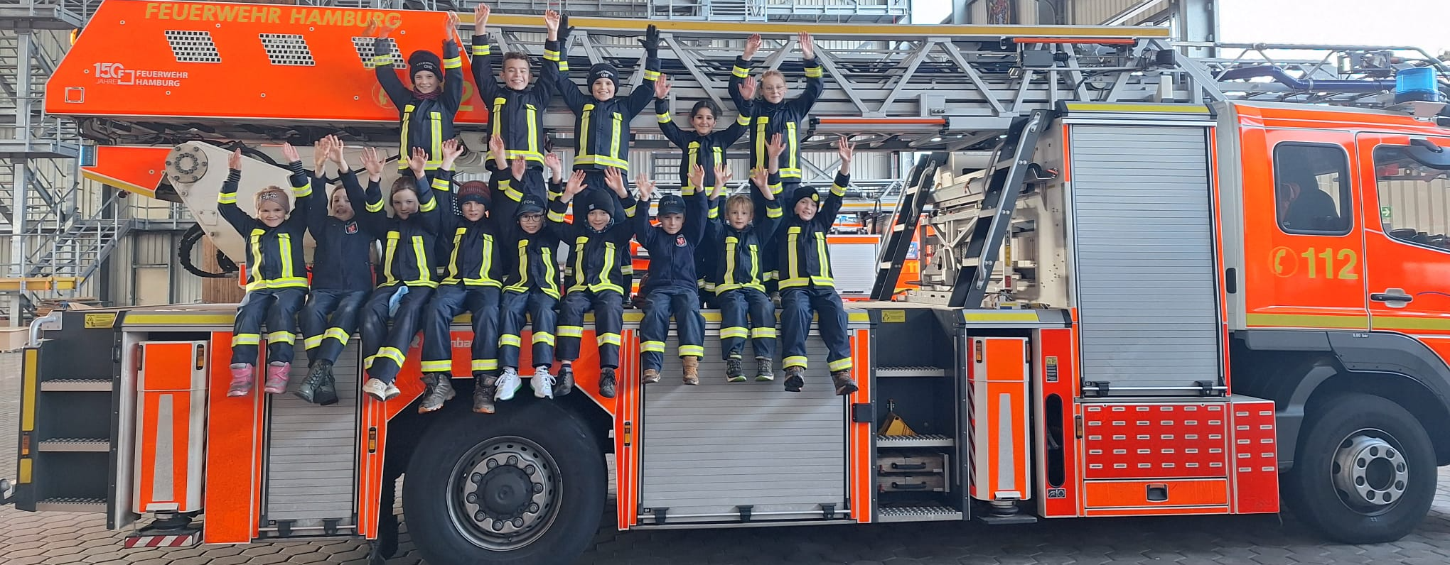 Kinderfeuerwehr Ohe bei einem Besuch – Gruppenfoto auf einem Feuerwehrfahrzeug